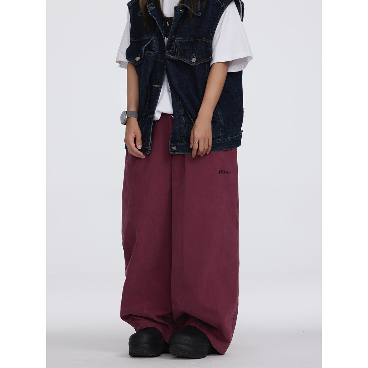 Model wearing burgundy wide-leg pants with an elastic waist, styled with a dark denim vest and white T-shirt.