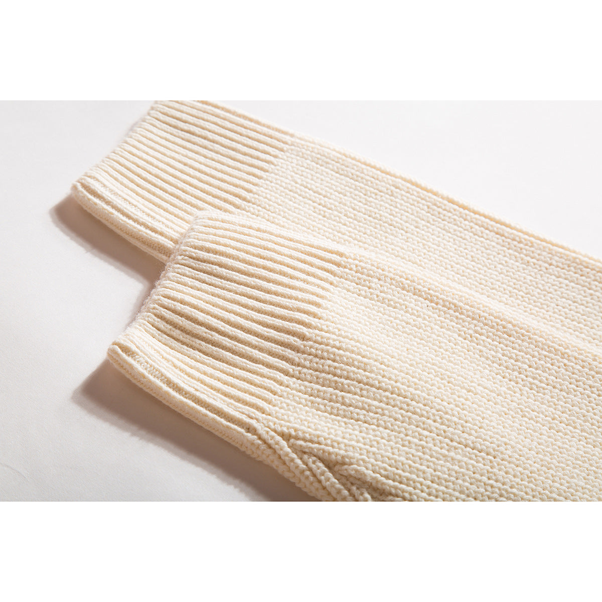 Close-up of the ivory sweater's ribbed sleeve cuff and textured knit.