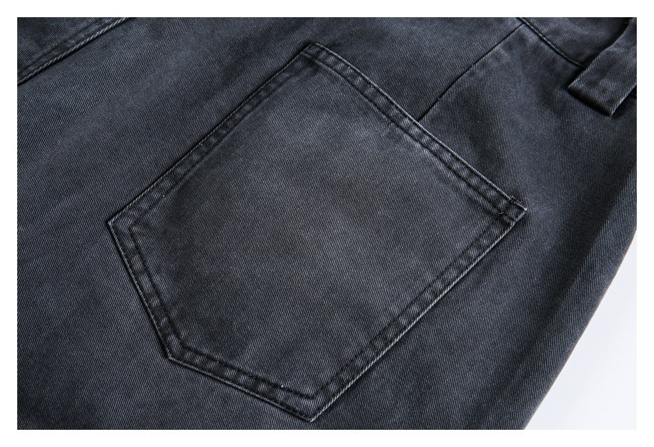 Close-up of a stitched patch pocket on dark charcoal denim.