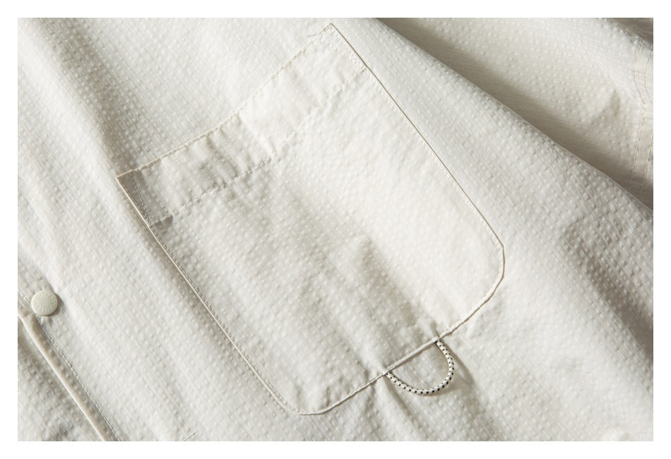 Close-up of the ivory shirt's large chest pocket with a loop detail.