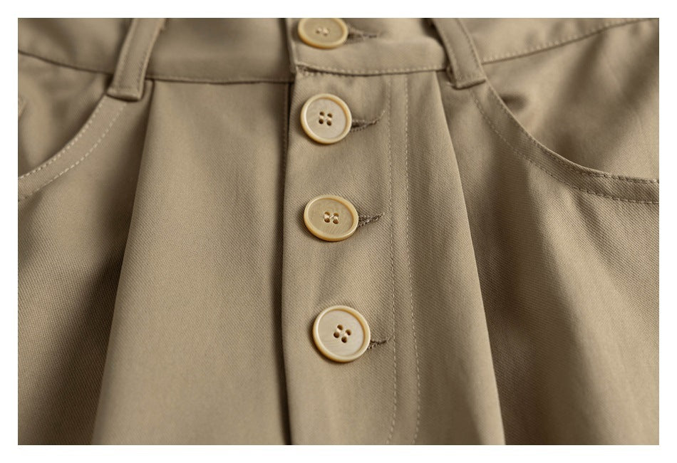 Close-up of tan trousers with a three-button front closure and curved front pockets.