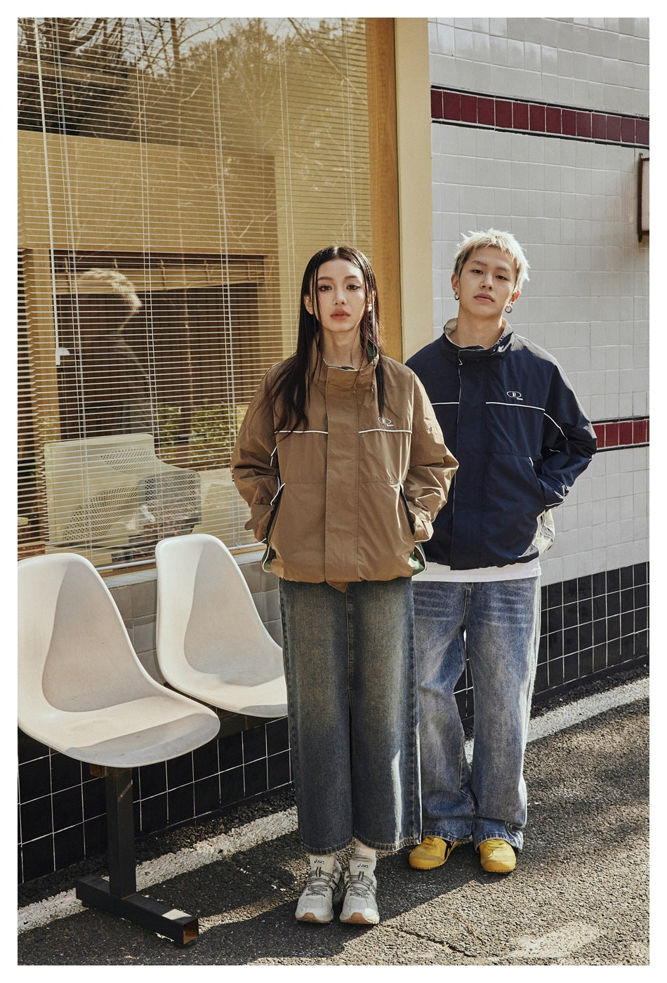 Two models show brown and navy high-collar jackets with white piping; both jackets have front pockets and small chest