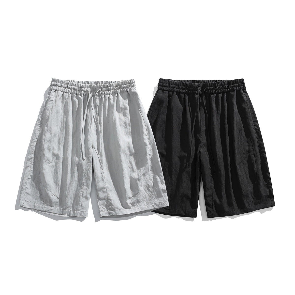 Front view of loose, knee-length drawstring shorts in light gray and black.