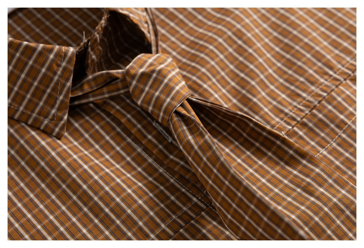 Close-up of a matching brown plaid tie draped across the shirt front.