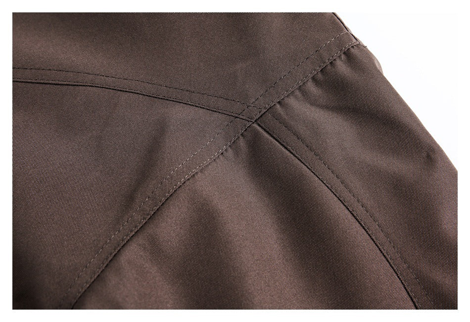 Close-up of dark brown coat fabric with curved stitched seams.