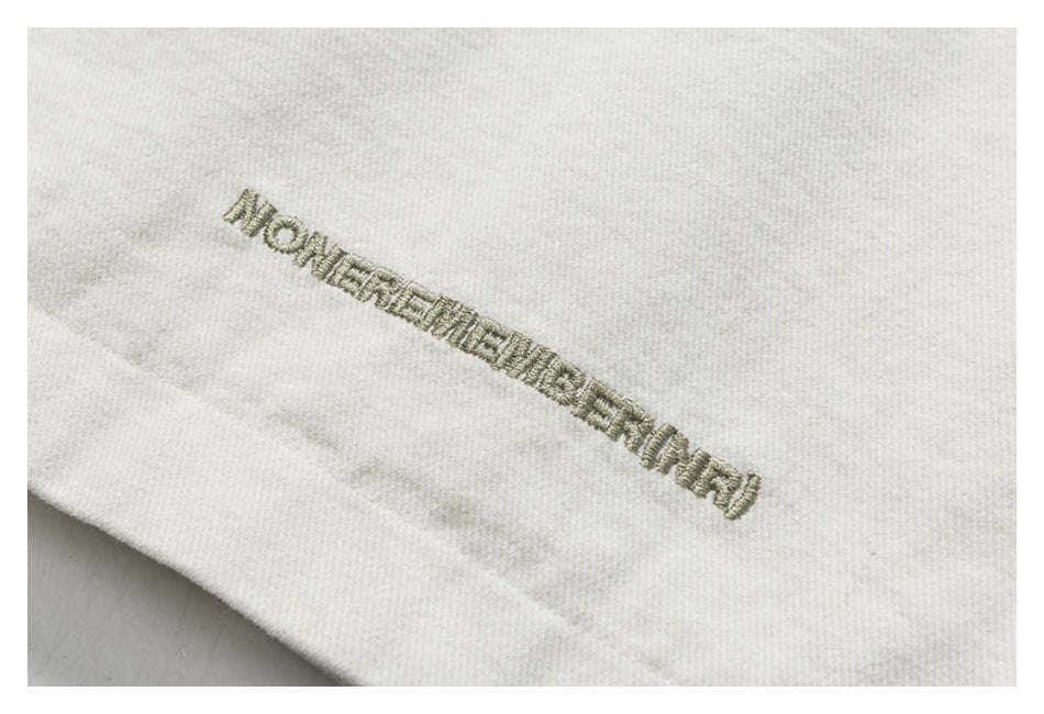 Close-up of embroidered lettering on off-white fabric.