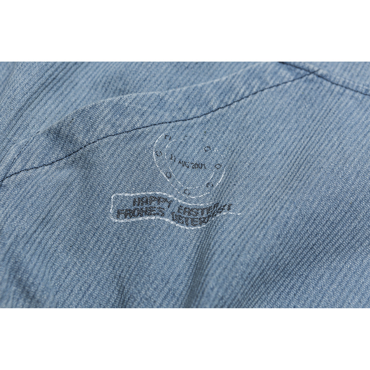 Close-up of a dark and white stitched graphic on light blue textured jacket fabric.