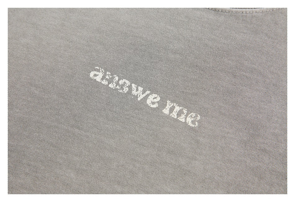 Close-up of a small white text design printed on light gray washed T-shirt fabric.