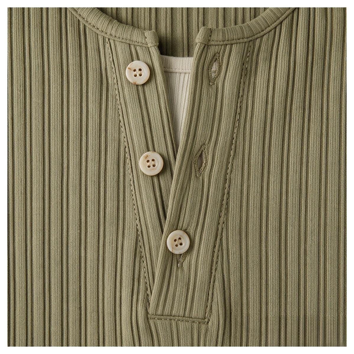 Close-up of the olive ribbed shirt's button placket, buttonholes and cream buttons.