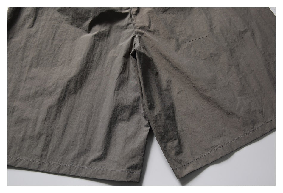 Partial flat-lay front view of charcoal-gray shorts, showing the leg openings and hem stitching.