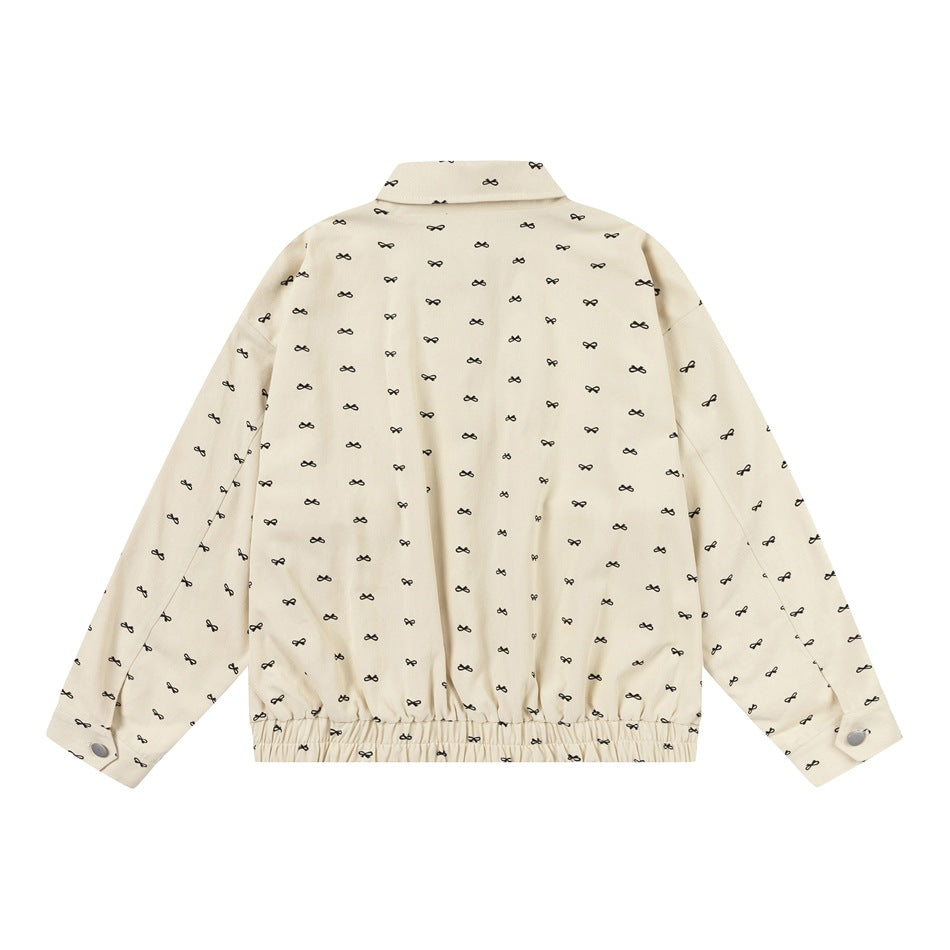 Back view of a cream jacket covered in small black bow motifs, with a collar, long sleeves and elasticated hem.