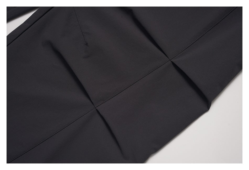 Close-up of black garment fabric with intersecting stitched panel seams.