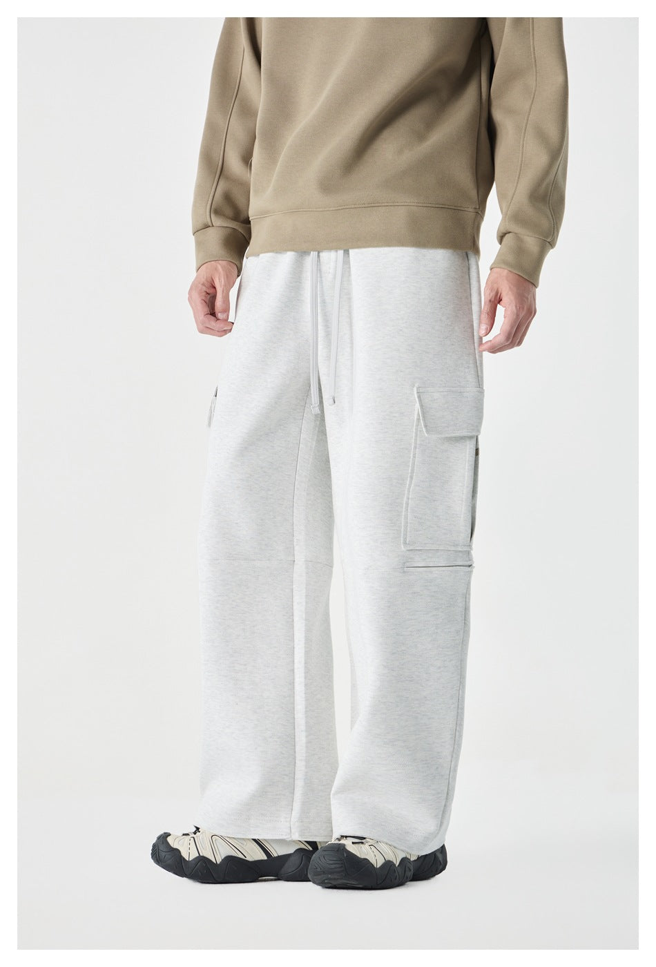 Model wearing gray wide-leg cargo pants with a tan sweatshirt, three-quarter view showing a side flap pocket