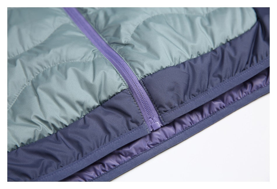 Close-up of a purple zipper joining blue-gray quilted fabric and a navy lower panel.