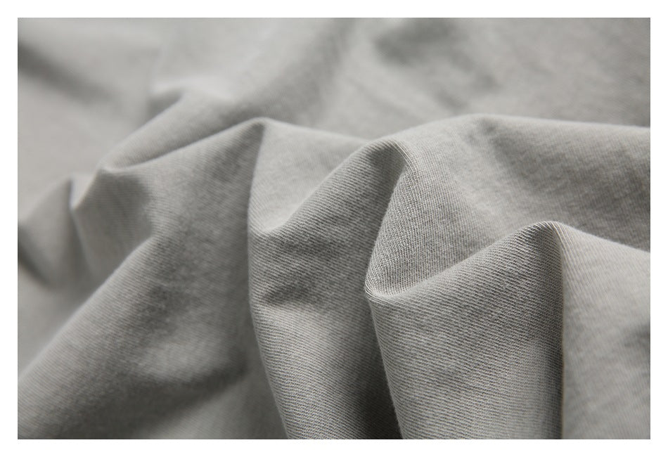 Close-up of light gray knit fabric arranged in soft folds, showing its surface texture.