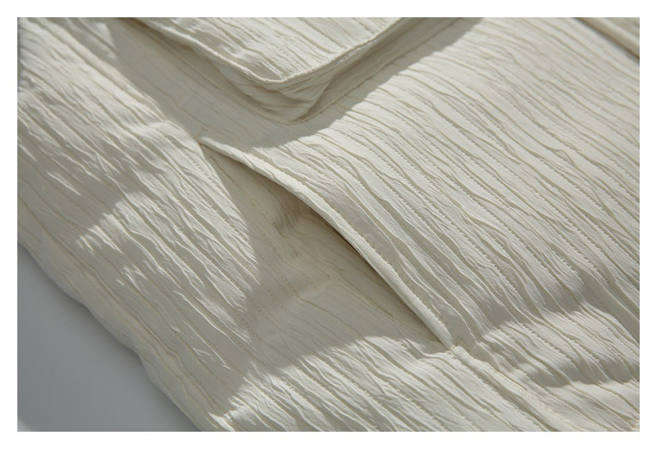 Close-up of the ivory vest's layered seams and deeply rippled fabric texture.
