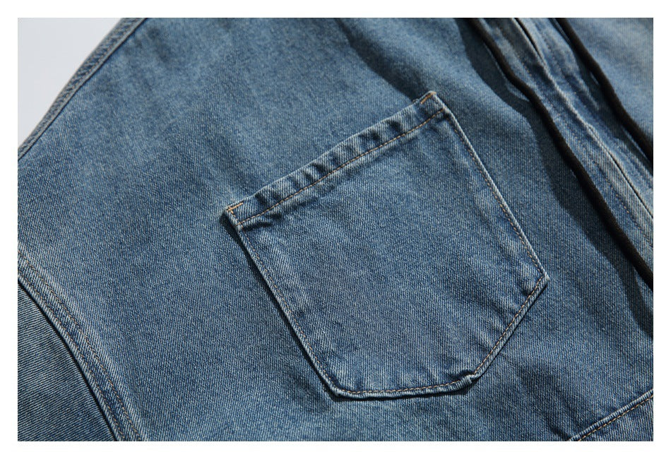 Close-up of a blue denim garment's stitched patch pocket and faded wash.
