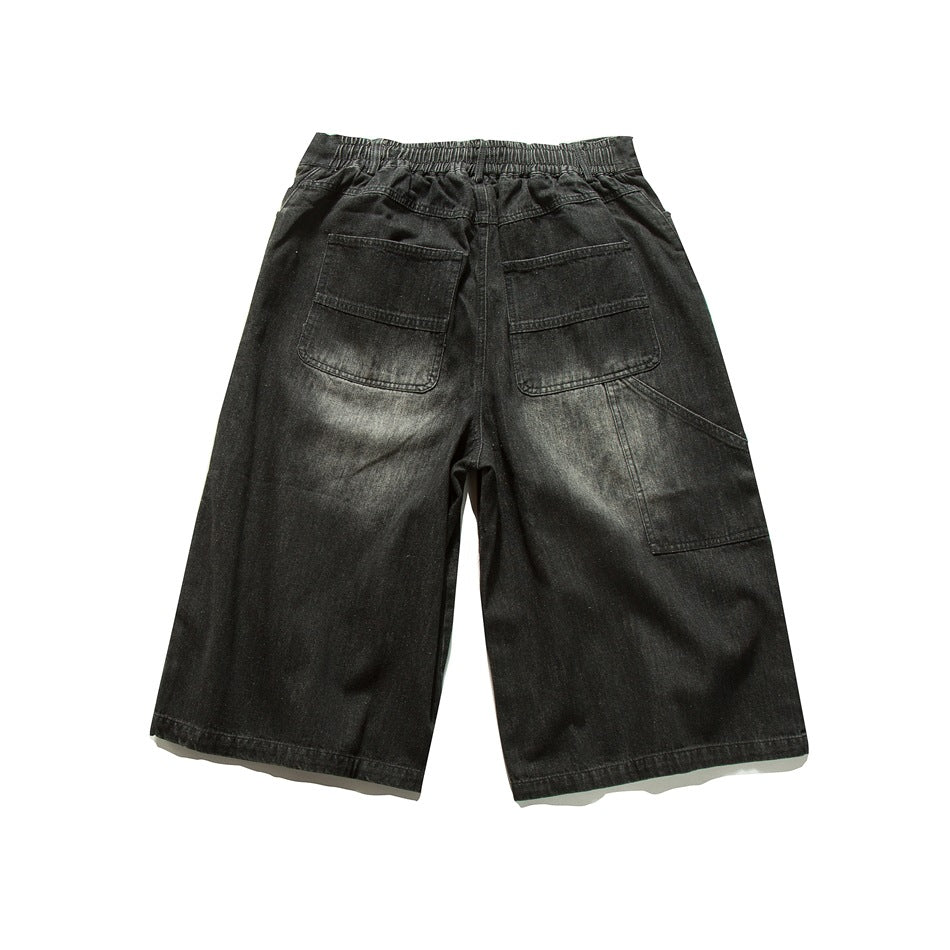 Back view of loose black denim shorts with an elastic waistband, two rear pockets and a large side pocket.