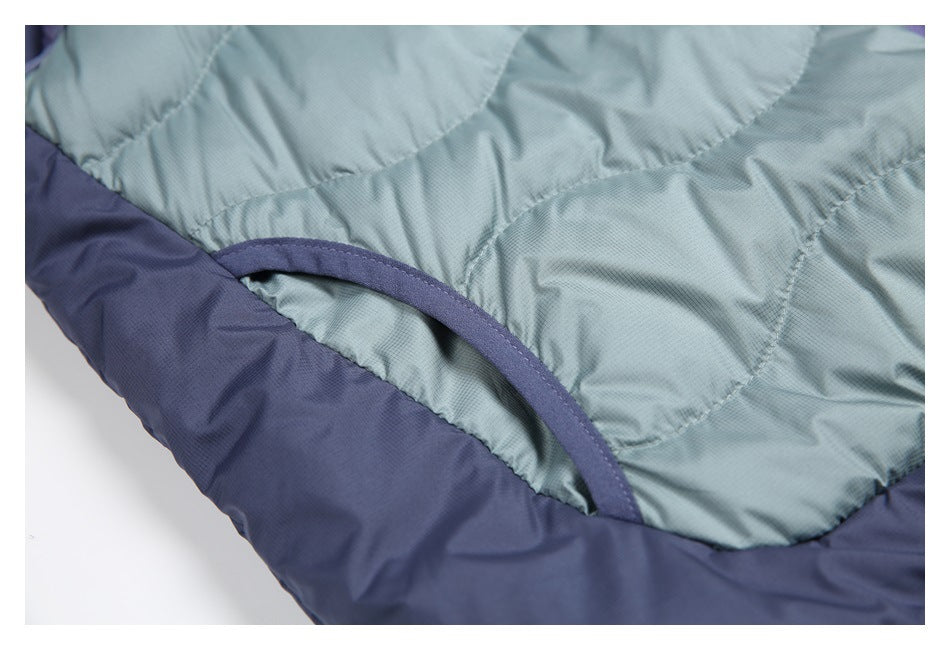 Close-up of the quilted green-blue vest body, curved bound opening, and navy trim.