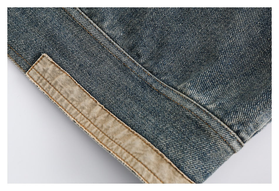 Close-up of blue denim with orange topstitching and a narrow strip of tan lining along the edge.