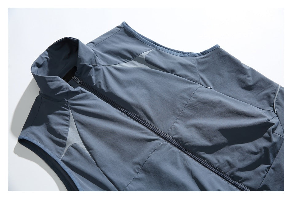 Close-up of a slate-blue vest front showing its stand collar, panel seams and diagonal zipper.