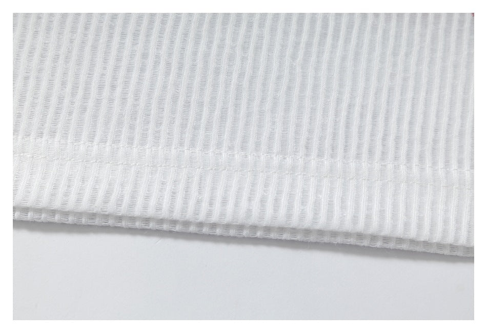 Close-up of white ribbed fabric folded to show its vertical texture and a horizontal seam.