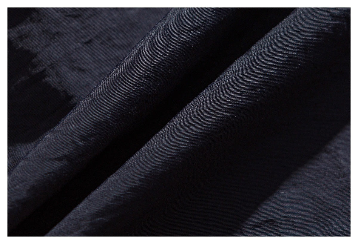 Close-up of dark navy-black fabric with a fine diagonal weave and soft folds.