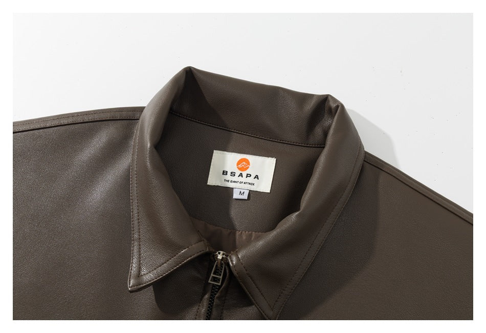 Close-up of a dark brown jacket’s pointed collar, front zipper, and sewn neck label.