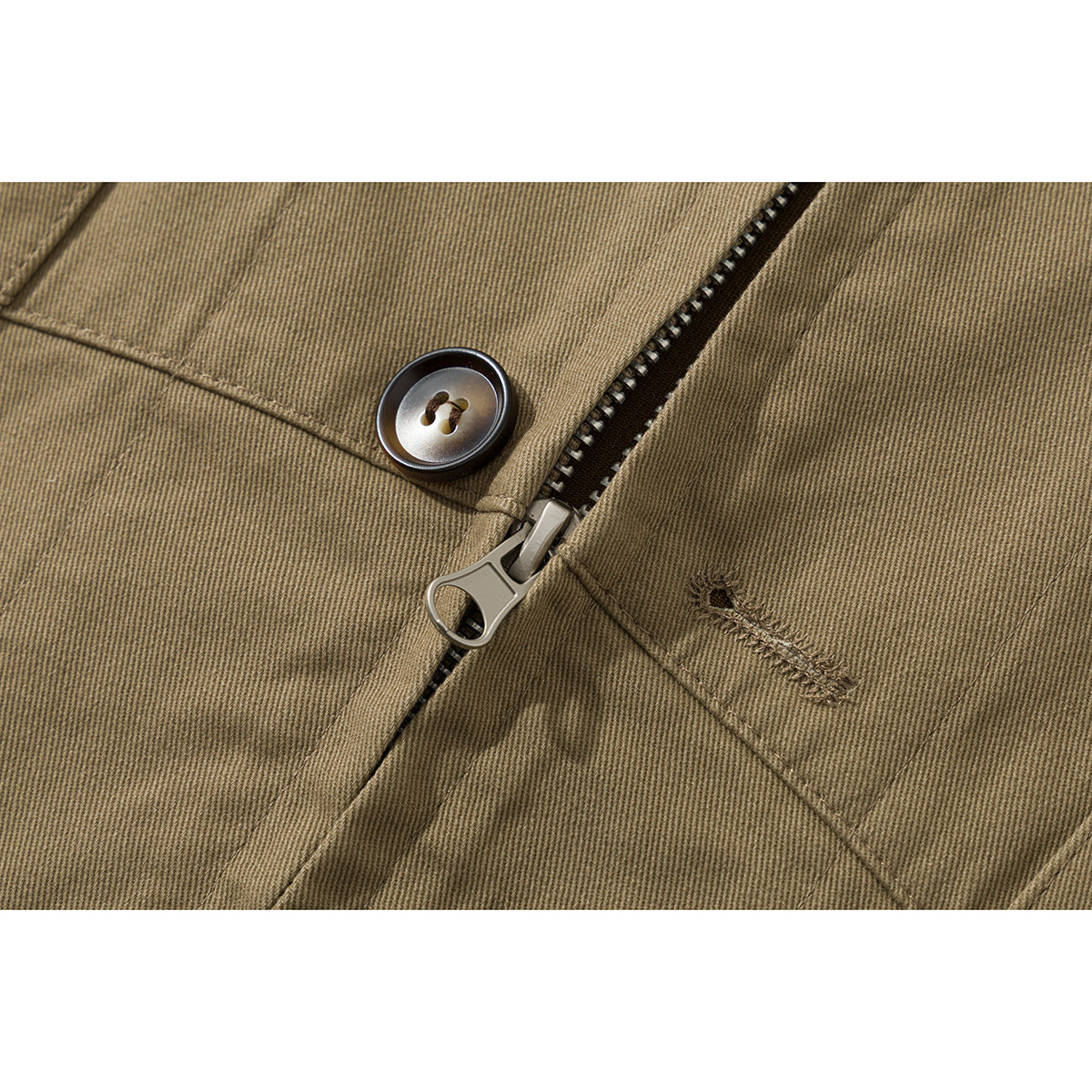 Close-up of a tan jacket’s zipper, dark button, stitching, and fabric texture.