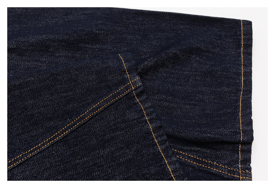Close-up of a dark indigo jeans leg hem with golden stitching.