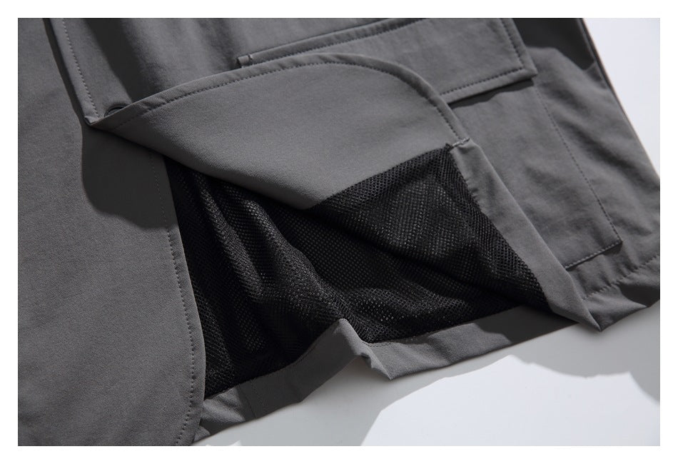 Close-up of a charcoal jacket with a pocket flap lifted to reveal black mesh inside.
