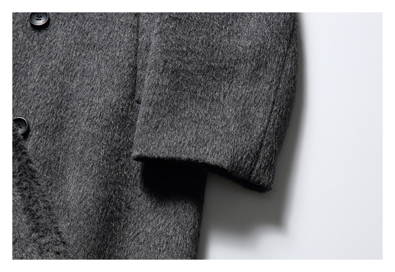 Close-up of a charcoal gray coat sleeve and cuff beside part of its buttoned front.
