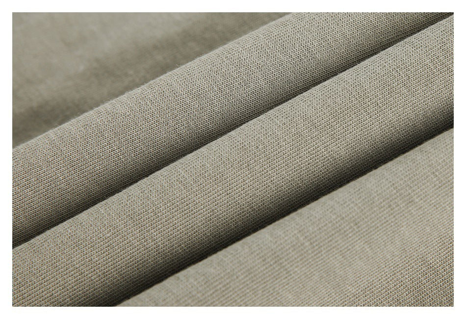 Close-up of light taupe-gray fabric folded into diagonal ridges, showing its textured surface.