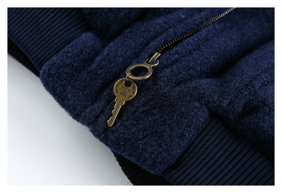Close-up of a dark navy garment with a metal zipper, key-shaped charm, and ribbed trim.