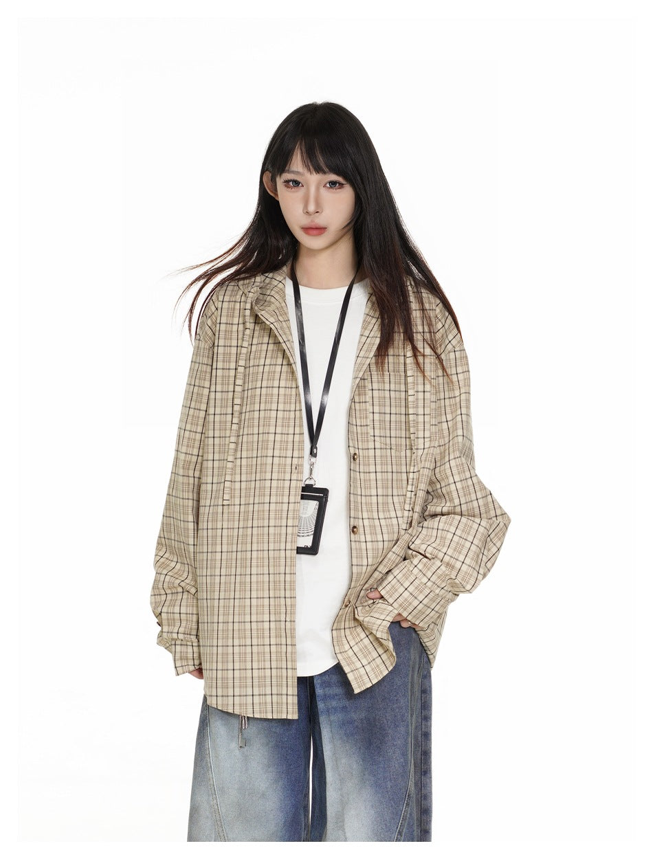 Closer front view of a model wearing a beige plaid overshirt over a white top and blue jeans.