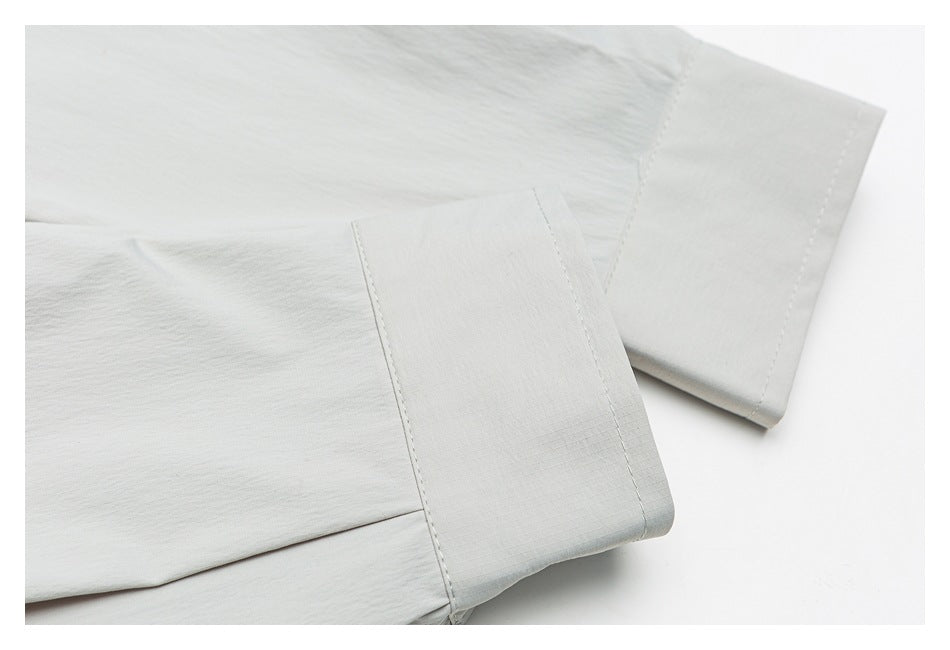 Close-up of a pale gray garment sleeve and wide stitched cuff laid flat.