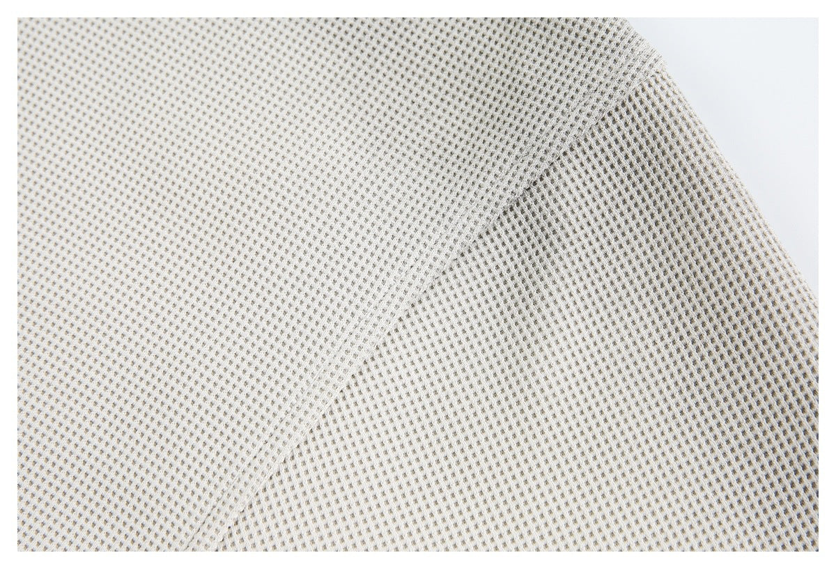 Close-up of ivory waffle-knit fabric with a diagonal seam and textured grid.