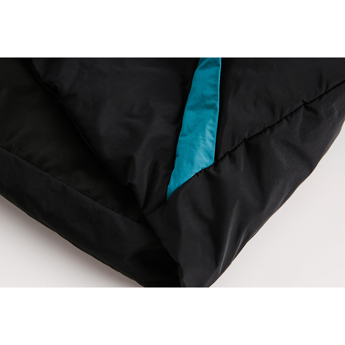 Close-up of black padded garment panels with a turquoise accent strip and stitched seams.