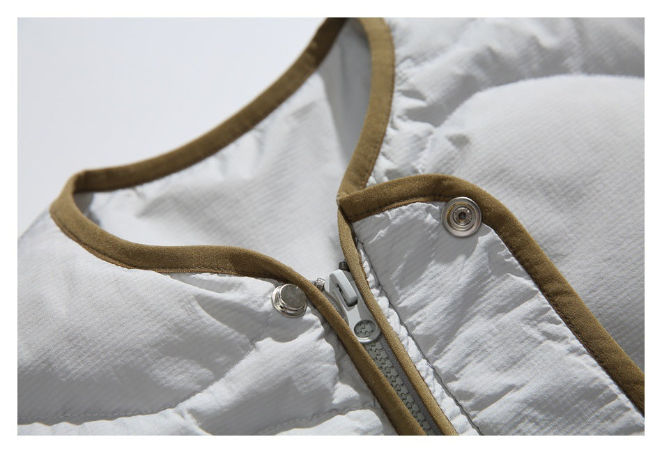 Close-up of a white quilted jacket neckline with tan-brown binding, a zipper, and metal snap buttons.