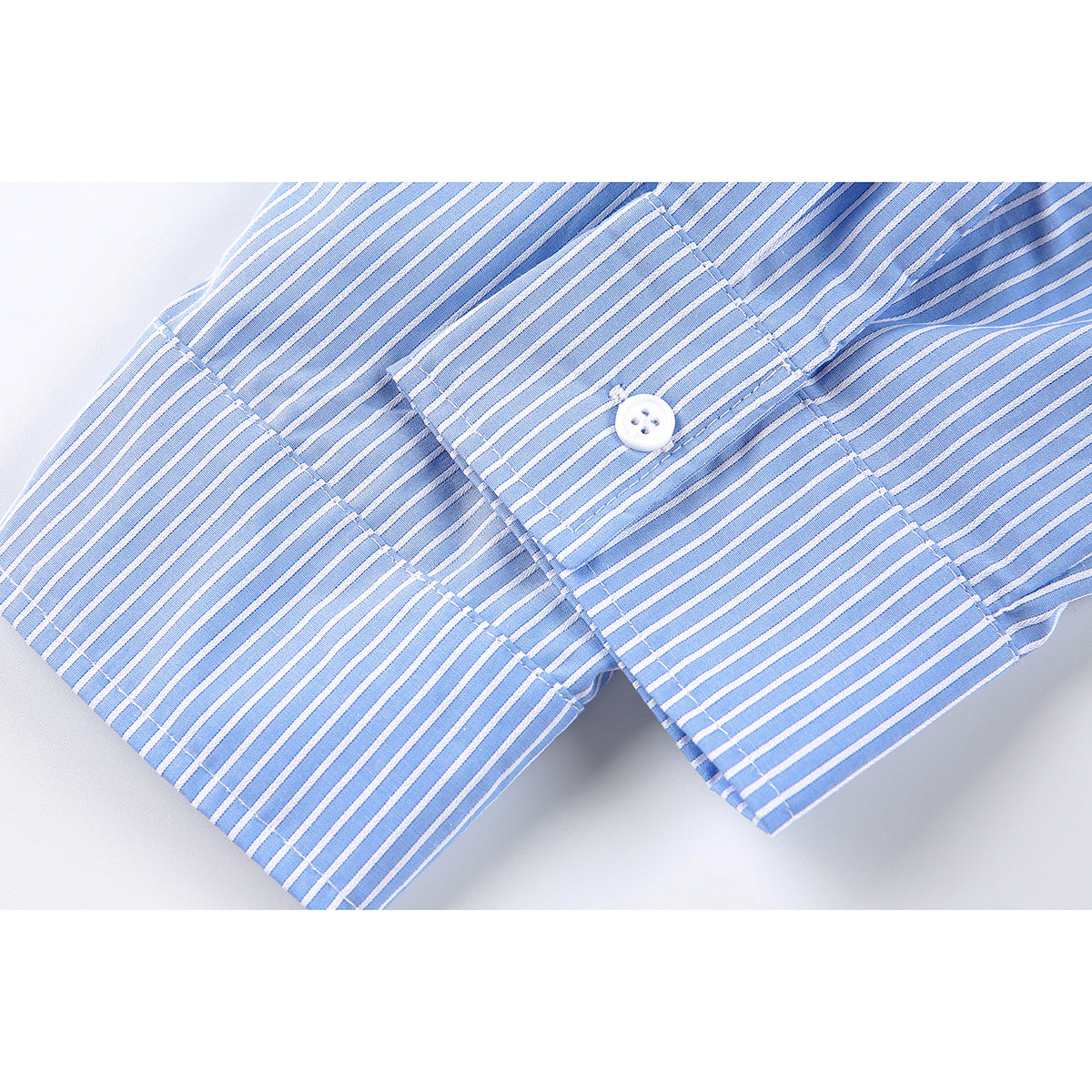 Close-up of a blue-and-white striped sleeve cuff with a white button and visible stitching.