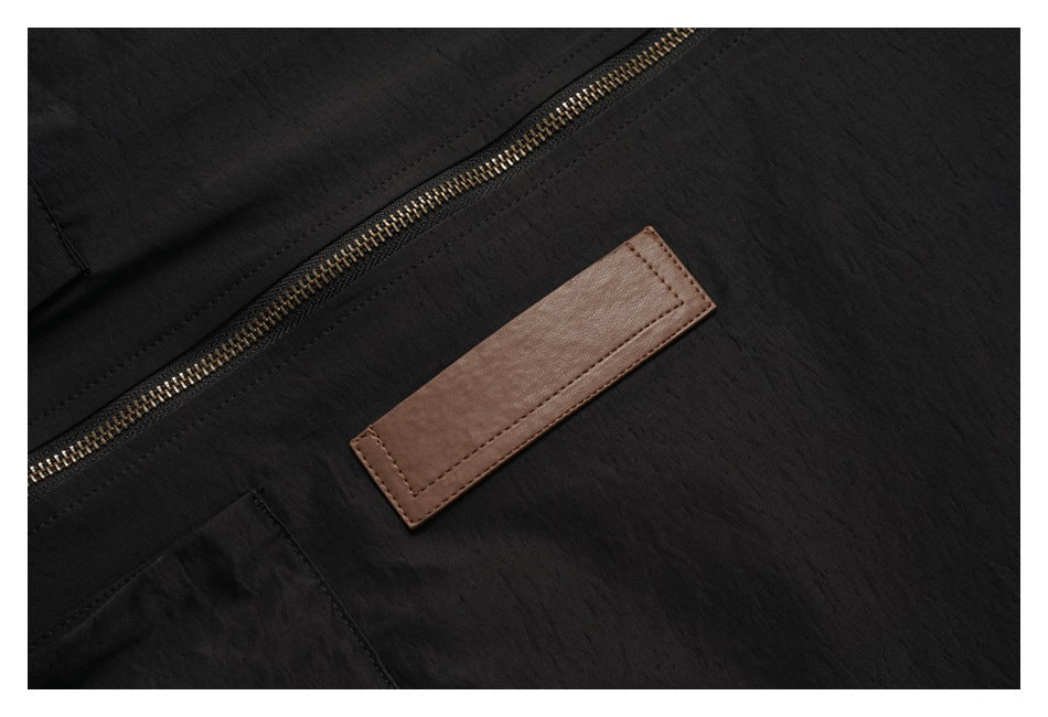 Close-up of a brass-tone zipper and blank brown rectangular patch on the black jacket.