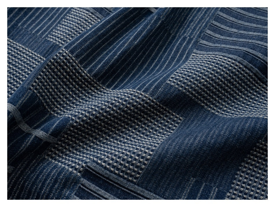 Close-up of the shirt’s dark blue fabric, showing contrasting woven patchwork textures and stripes.