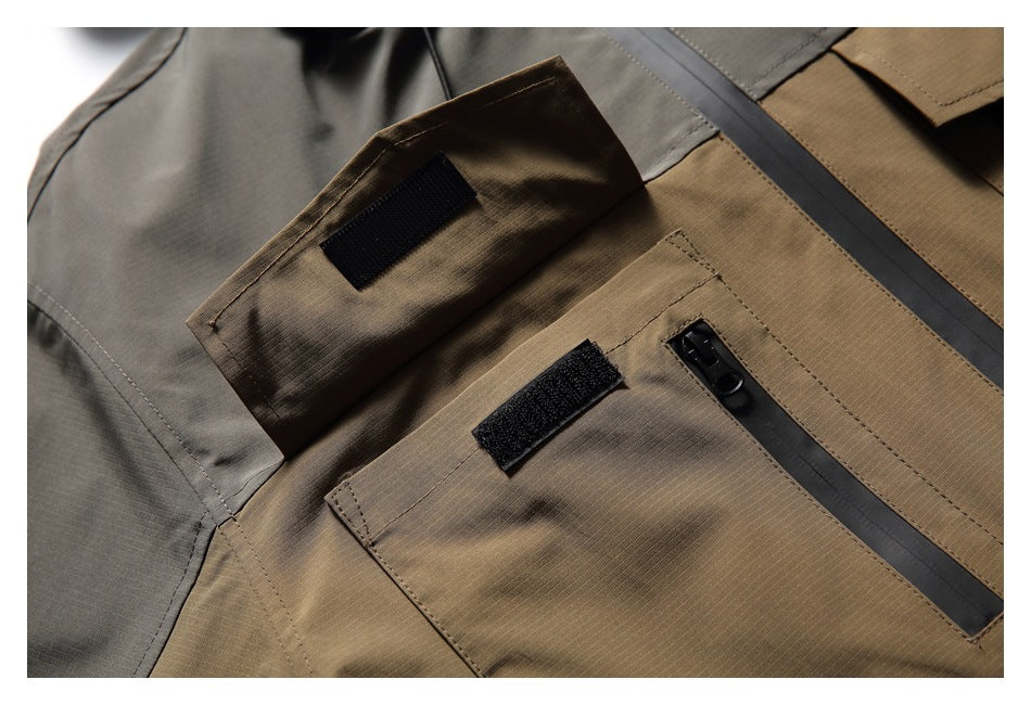 Close-up of a brown and gray jacket with flap pockets, black hook-and-loop tabs and a dark zipper.