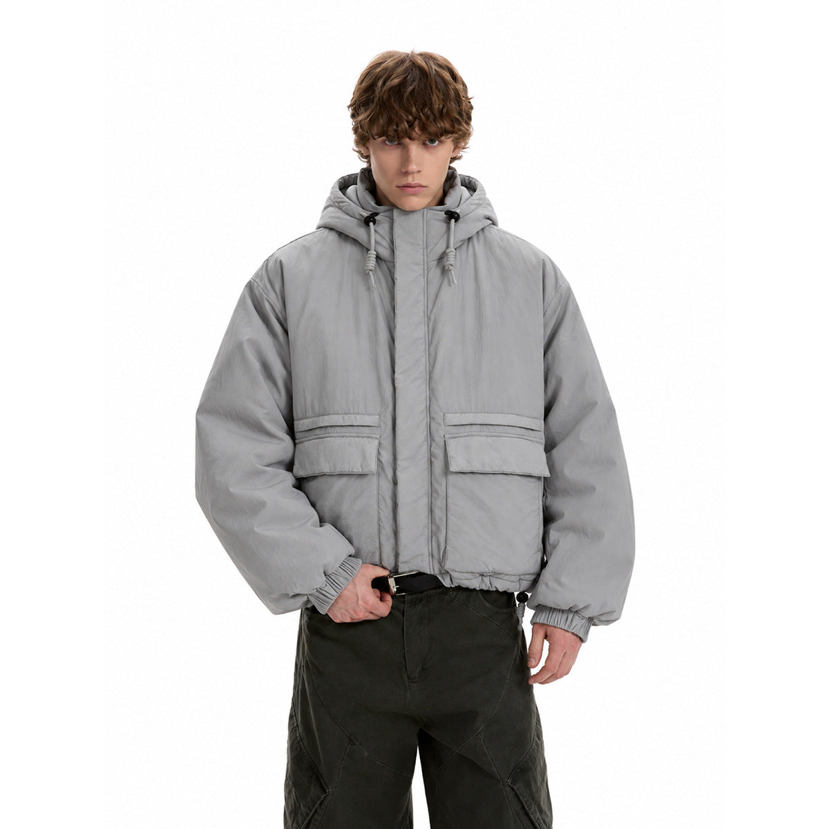Model wearing a light gray hooded jacket with a front storm flap, drawcord hood, oversized flap pockets and elastic cuffs.