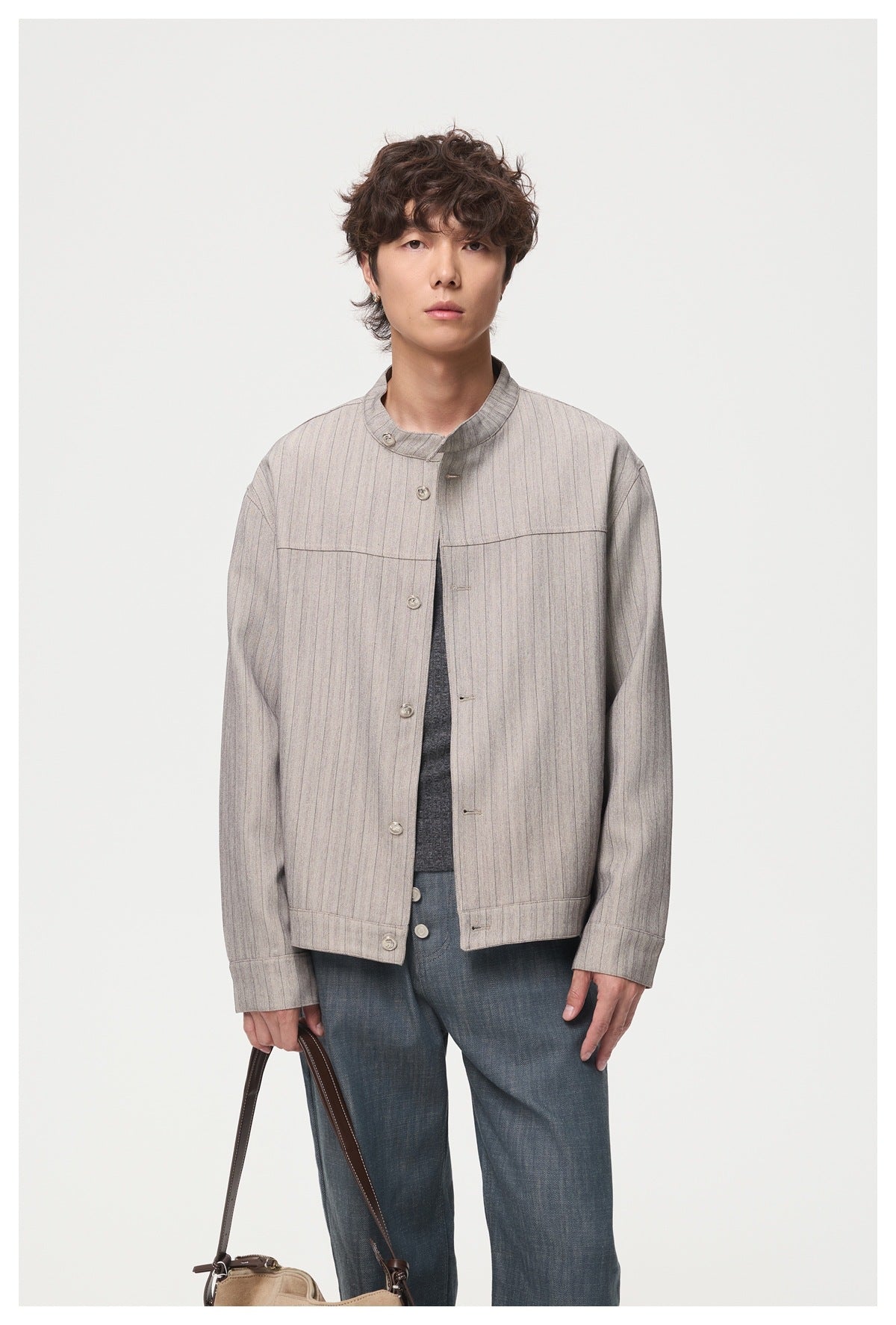 Model wearing an open light gray pinstriped jacket with a stand collar, dark shirt, and blue trousers.