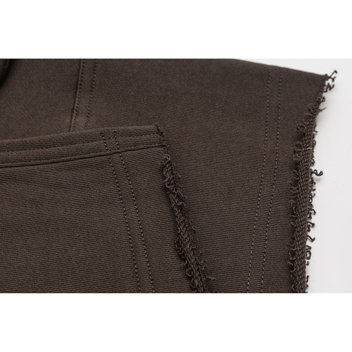 Close-up of brown shorts showing stitched seams and a raw, frayed hem.