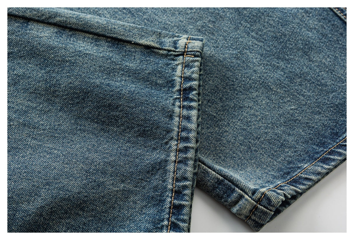 Close-up of blue denim with a stitched hem and faded wash.