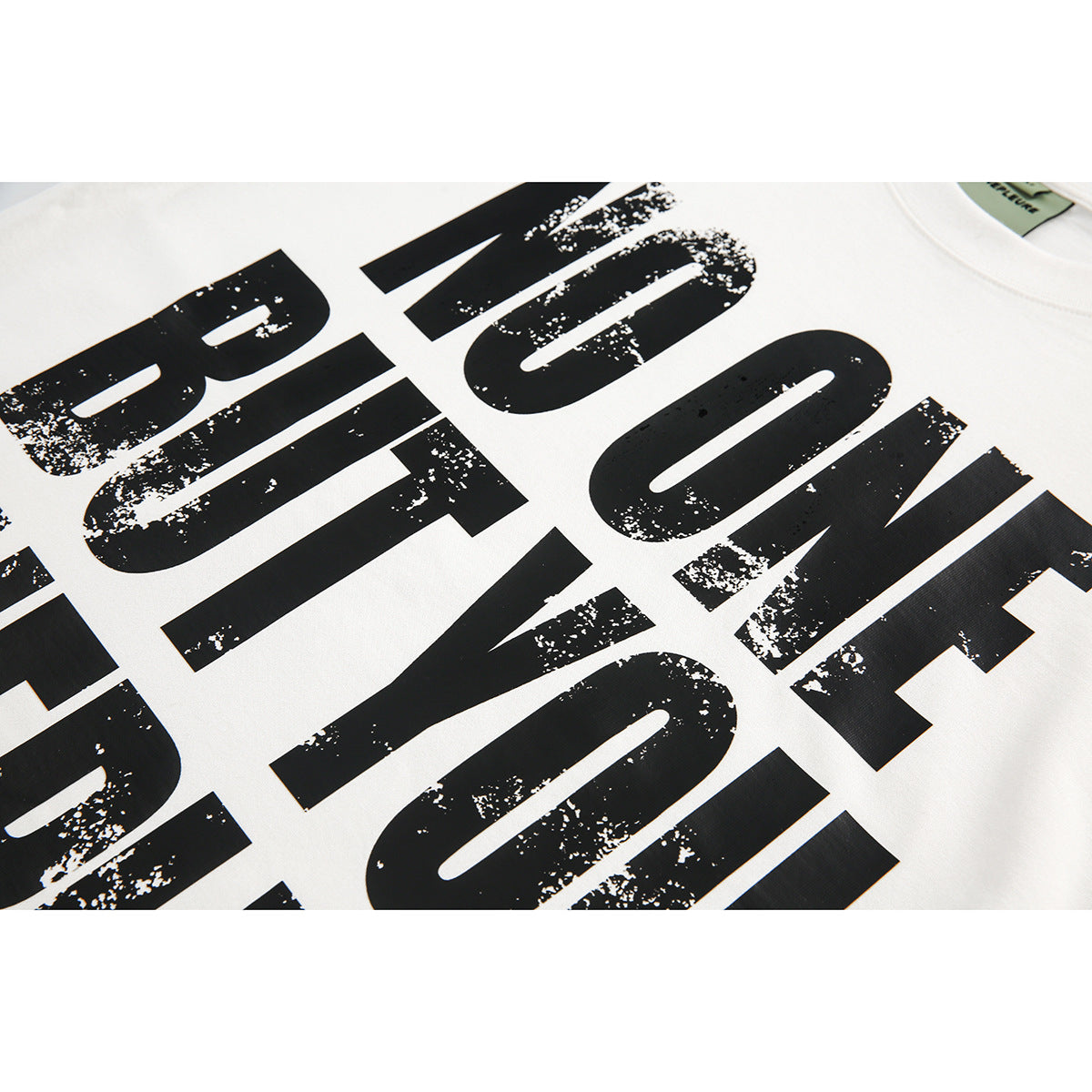 Close-up of distressed black lettering printed on a white T-shirt.