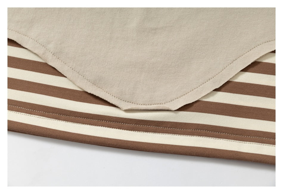 Close-up of a beige T-shirt hem layered over a brown-and-cream striped garment.
