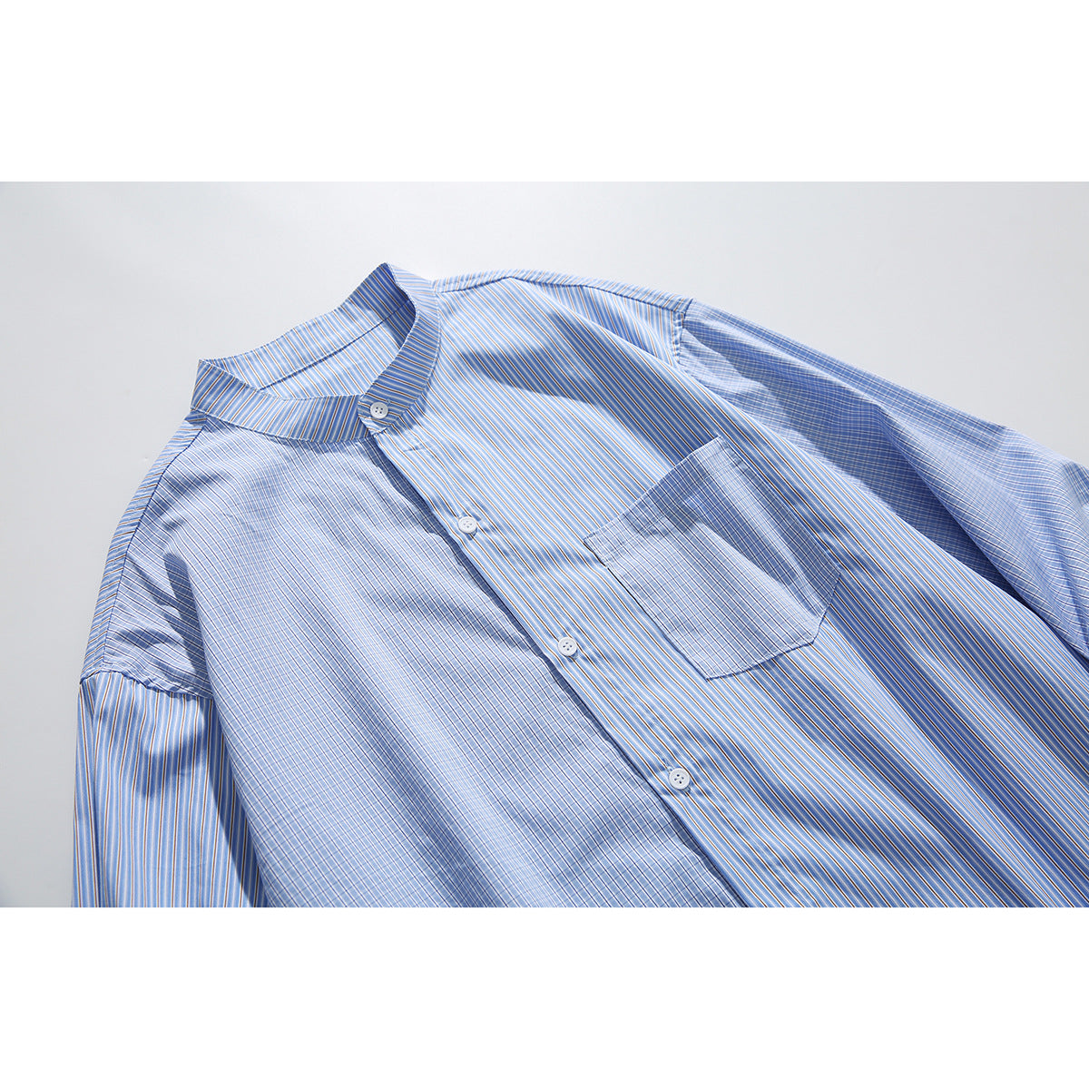 Flat-lay close view of a blue striped button-up shirt with a band collar and chest pocket.